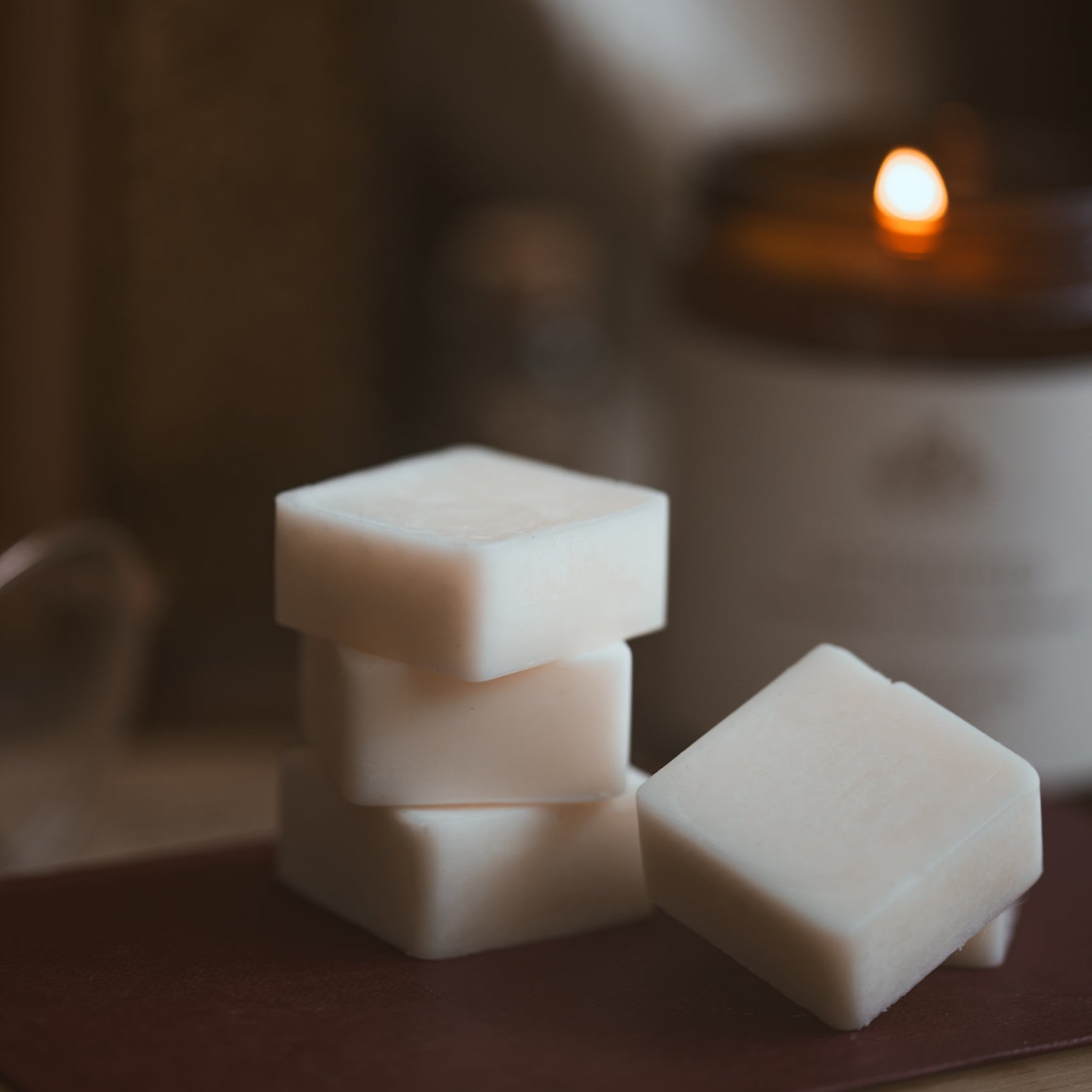 Stack of wax melt cubes on a book with a blurred candle in the background